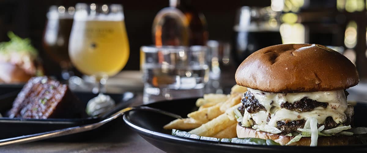 burger and fries on plate with beer in background
